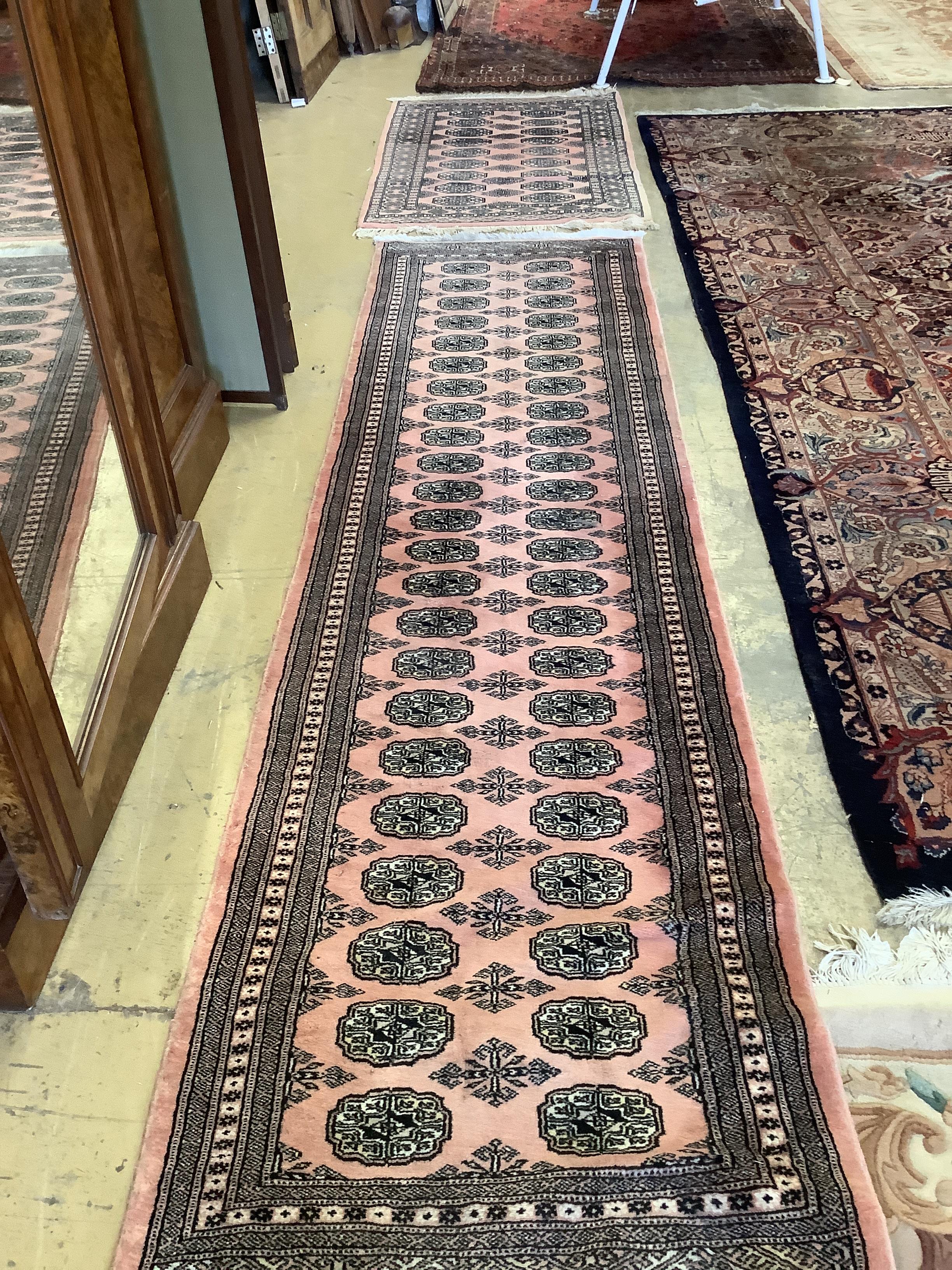 A Bokhara peach ground runner, 310 x 83cm together with a similar rug